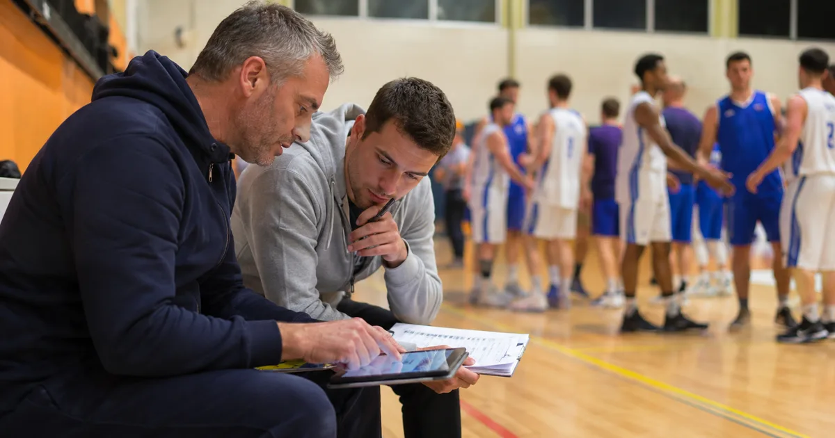 Coach calculant l'évaluation des joueurs sur une feuille de statistiques de basket